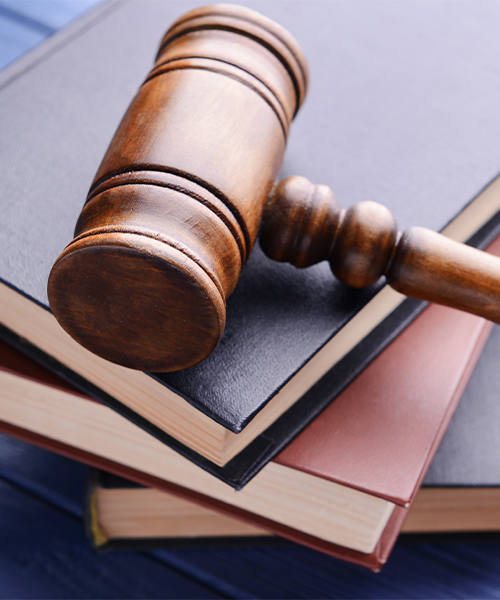 Wooden judge’s gavel resting on top of stacked legal books, symbolizing law and justice.